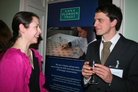 Two alumni in front of the new Anna Plowden Trust banner