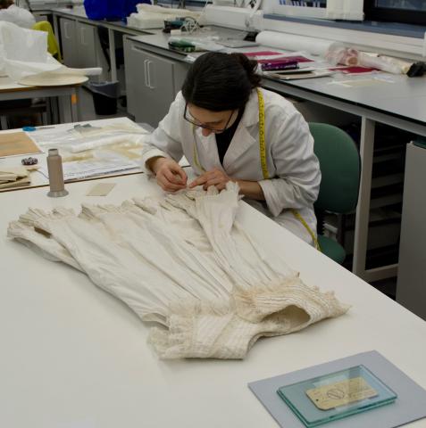 Applying a stitched support to an Edwardian child's pinafore