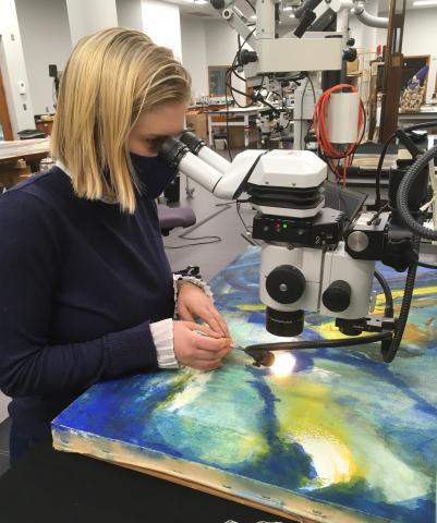 Anna Vesaluoma removing accretions under the microscope from the 20th century painting by Franz Kline. 