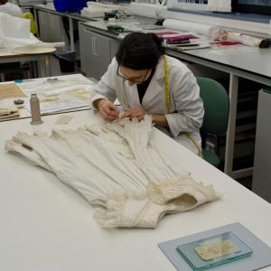 Applying a stitched support to an Edwardian child's pinafore