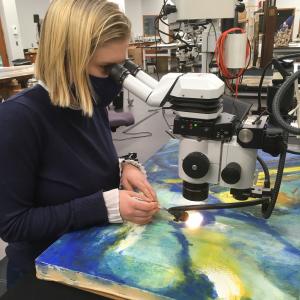 Anna Vesaluoma removing accretions under the microscope from the 20th century painting by Franz Kline. 